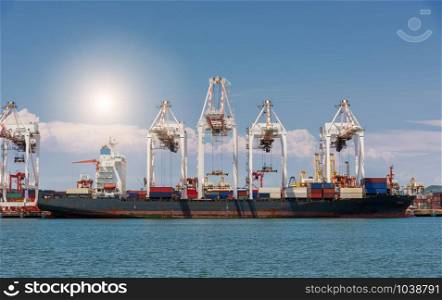 Cranes loading containers on large port cargo transport ship at day time