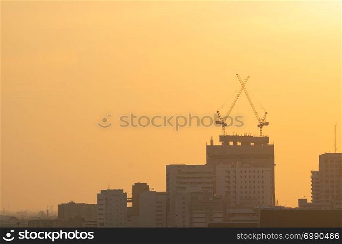 Cranes on construction site. On building skyscraper in sunset.