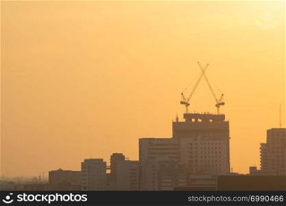 Cranes on construction site. On building skyscraper in sunset.
