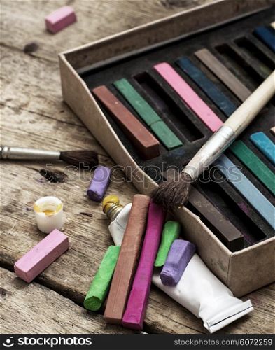 Crayons and paints. Crayons and paints for painting on wooden background