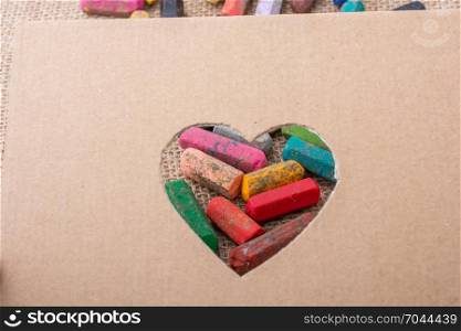 Crayons seen through heart shape cut out of cardboard