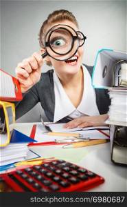 Craziness and satisfaction from work. Crazy bizarre funny secretary accountant businesswoman with big loupe. Woman surrounded by business equipment.. Crazy bizarre businesswoman with big loupe.