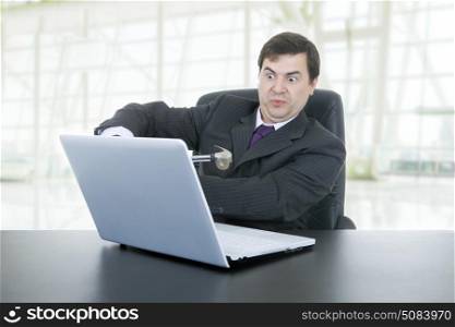 crazy businessman with a hammer smashing a laptop, at the office
