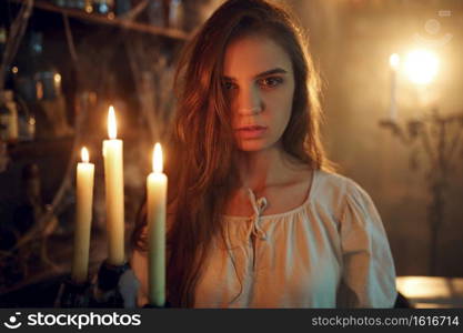 Crazy demonic woman with candle choosing potions, demons casting out. Exorcism, mystery paranormal ritual, dark religion, night horror. Crazy demonic woman with candle choosing potions