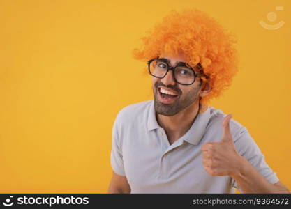 Crazy funny young man wearing party glasses with orange wig