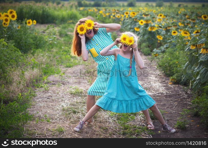 Crazy happy girls in a field of sunflowers at sunset. family - mom and daughter. Ukraine.