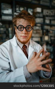 Crazy male scientist in glasses working in laboratory. Electrical testing tools on background. Lab equipment, engineering workshop