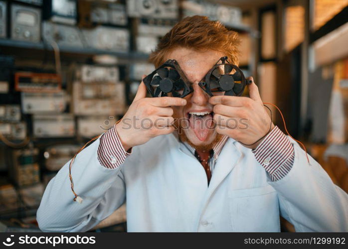 Crazy scientist with fans instead of eyes in laboratory. Electrical testing tools on background. Lab equipment, engineering workshop