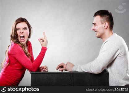 Crazy woman showing middle finger gesture to man. Insane girl gesturing in front of guy. Bad date dating.. Woman showing middle finger gesture to man