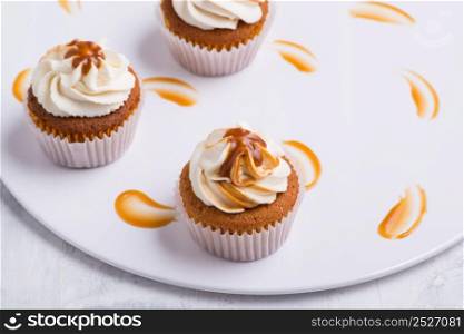 cream cupcake on white plate, top view, close-up. sweets on white background