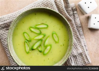 Cream of green asparagus soup in bowl, garnished with sliced asparagus on top, photographed overhead (Selective Focus, Focus on the soup) . Cream of Green Asparagus Soup