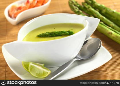 Cream of green asparagus with shrimps in the back (Selective Focus, Focus on the asparagus head on the soup). Cream of Asparagus