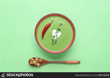 Cream soup bowl, homemade from spinach, on a green paper background. Minimal style spinach soup. Above view of healthy vegetable bowl soup.