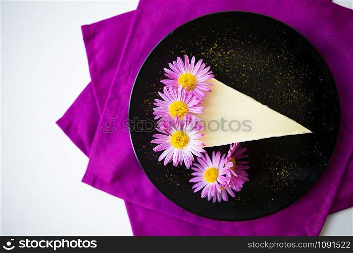 creamy cheesecake decorated with purple flowers on a bright napkin.. creamy cheesecake decorated with purple flowers on a bright napkin