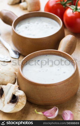 Creamy mushroom soup in two clay pots on a wooden table. Mushroom soup in clay pots