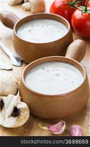 Creamy mushroom soup in two clay pots on a wooden table. Mushroom soup in clay pots