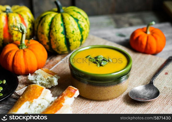 Creamy pumpkin soup with seeds on wooden background