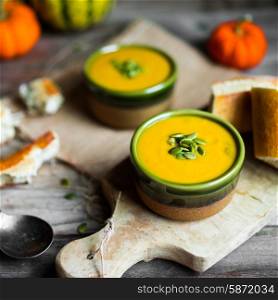 Creamy pumpkin soup with seeds on wooden background