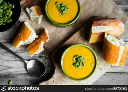 Creamy pumpkin soup with seeds on wooden background