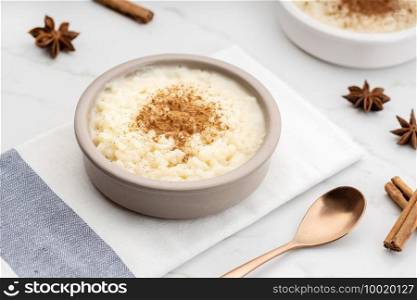 Creamy rice pudding with cinnamon in bowl on white marble table. Typical Spanish dessert
