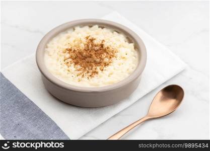 Creamy rice pudding with cinnamon in bowl on white marble table. Typical Spanish dessert