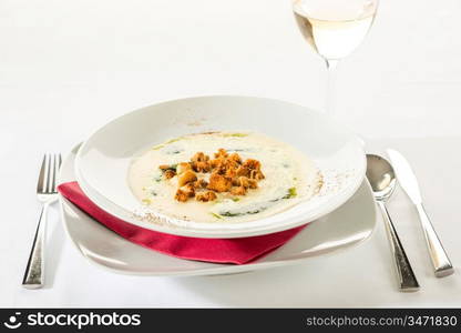 Creamy soup with garlic, spinach and croutons in white plate