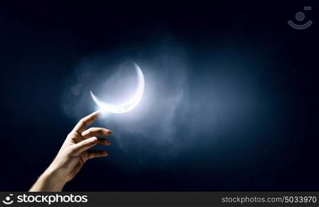 Creation concept. Close up of human hand touching with finger moon