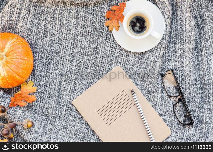 Creative autumn flat lay overhead top view stylish home workspace with notebook coffee cup cozy gray knitted plaid background copy space. Fall season template for feminine blog social media