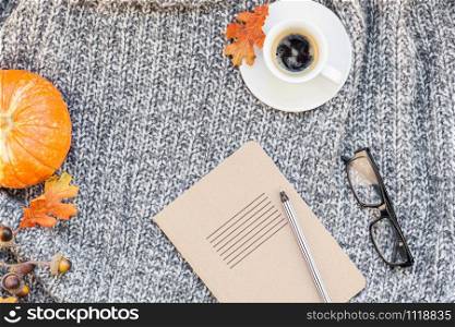 Creative autumn flat lay overhead top view stylish home workspace with notebook coffee cup cozy gray knitted plaid background copy space. Fall season template for feminine blog social media