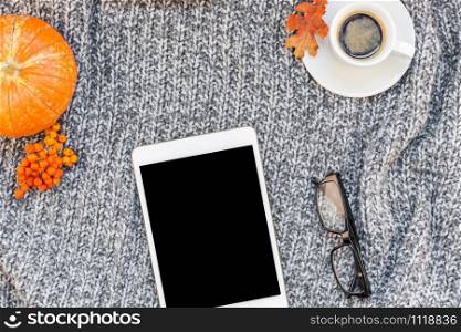 Creative autumn flat lay overhead top view stylish home workspace with tablet notebook coffee cup cozy gray knitted plaid background copy space. Fall season template for feminine blog social media