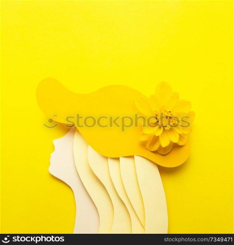 Creative beauty fashion concept photo portrait of woman girl made of paper in hat clothes accessories with natural flower on yellow background.