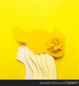 Creative beauty fashion concept photo portrait of woman girl made of paper in hat clothes accessories with natural flower on yellow background.