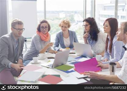 Creative business colleagues analyzing photographs at conference table in office