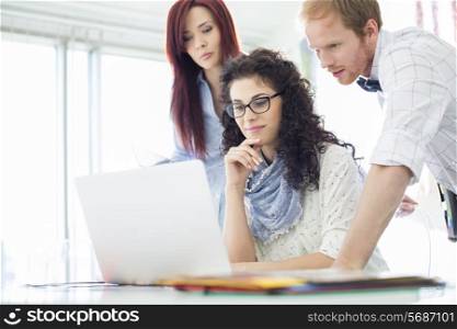 Creative business colleagues using laptop at desk in office