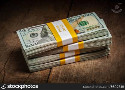 Creative business finance making money concept - stacks of new 100 US dollars 2013 edition banknotes bills bundles on wooden background