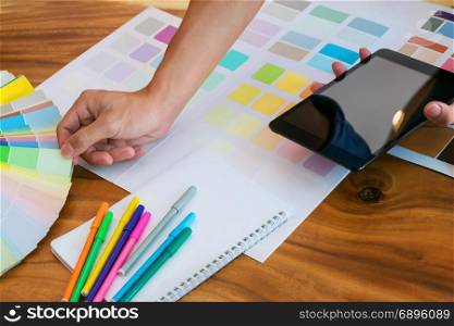 Creative business woman using tablet and working on colour charts on desk at a modern office