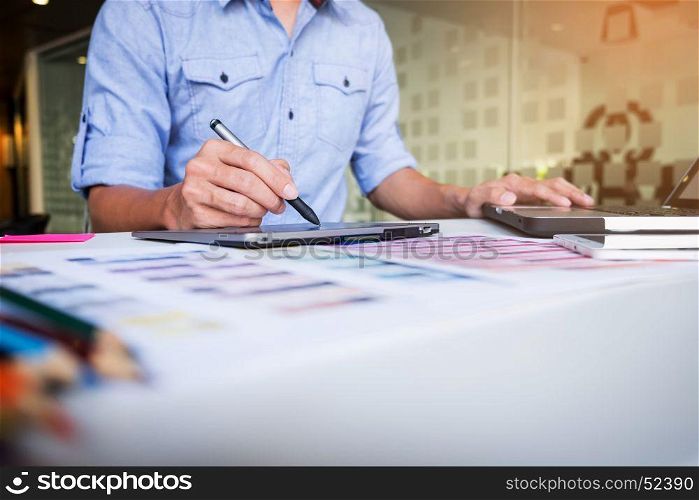 Creative businessman or designer writing on graphic tablet while using laptop in office.