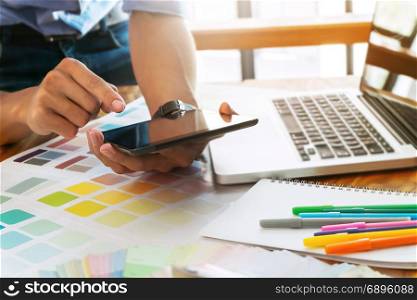 Creative businessman using tablet and working on colour charts on desk at a modern office