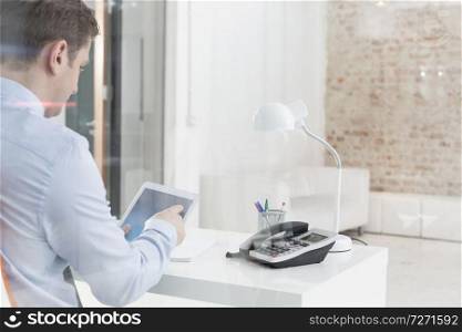 Creative businessman using tablet computer at desk in office