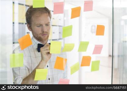 Creative businessman writing on sticky paper at office