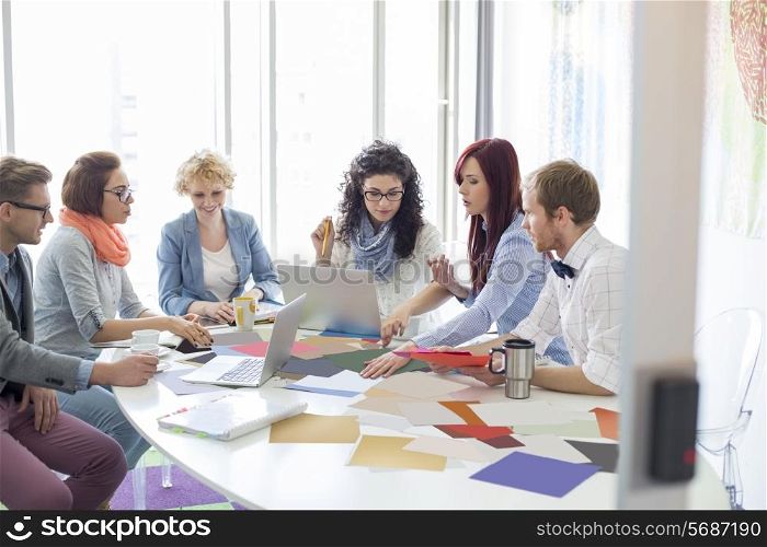 Creative businesspeople analyzing photographs at conference table in office