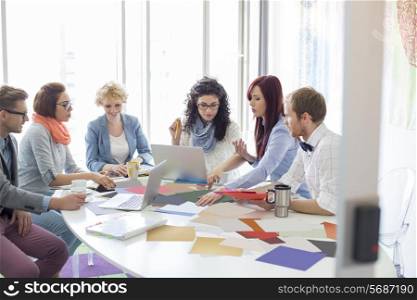 Creative businesspeople analyzing photographs at conference table in office