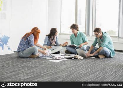 Creative businesspeople discussing while sitting on floor in office
