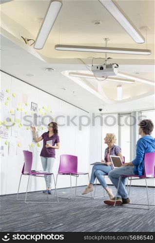Creative businesswoman giving presentation to colleagues in office