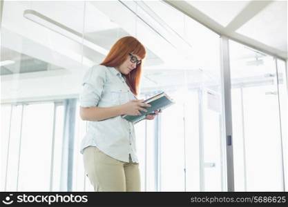 Creative businesswoman reading file in office