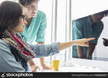 Creative businesswoman showing something to colleague on desktop computer in office