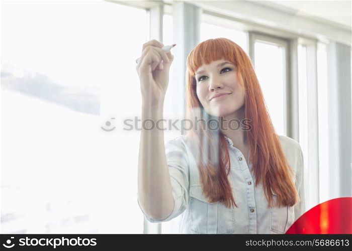 Creative businesswoman writing on glass wall in office