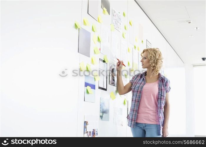 Creative businesswoman writing on sticky paper in office