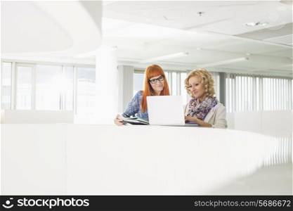 Creative businesswomen using laptop together in office