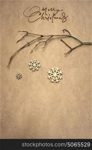 Creative christmas concept photo of a branch with snowflakes on brown background.